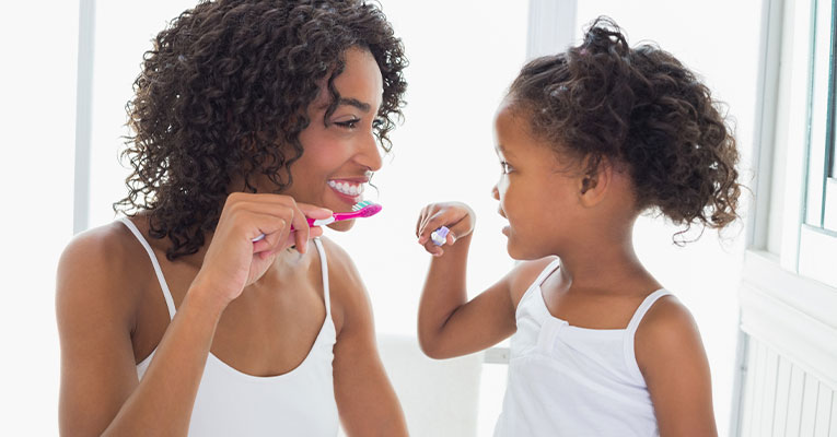 mom and child brushing teeth together